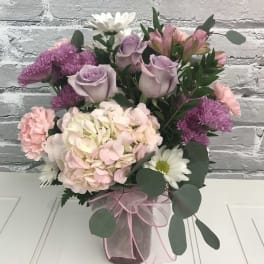 Pink and lavender bouquet in a glass vase with white daisies