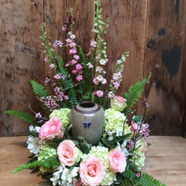 Pink roses and white flowers arranged around a ceramic urn