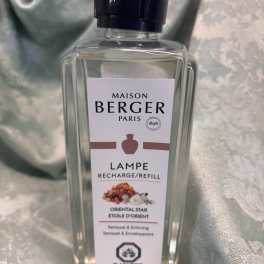Clear Maison Berger refill bottle with a black cap on a satin background