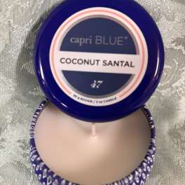 Blue-lidded candle tin labeled Coconut Santal on a patterned surface