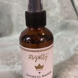 Amber room spray bottle with a pink label and black spray top