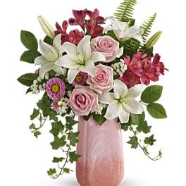 Pink roses and white lilies in a pink vase with trailing ivy