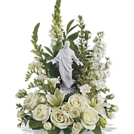 White floral arrangement with a small religious statue in the center