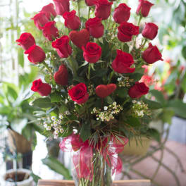 Red roses in a clear glass vase with glittery heart picks