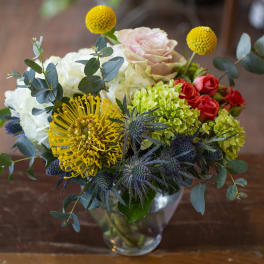 Mixed bouquet in a clear glass vase with yellow, white, pink, and red blooms