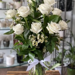 Bouquet of white roses in a clear glass vase with a white ribbon