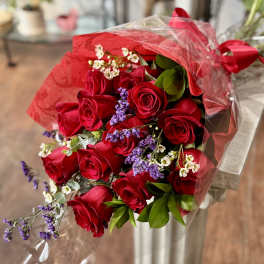 Bouquet of red roses with purple filler flowers wrapped in red and clear plastic