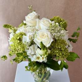 White roses and green hydrangeas in a clear glass vase