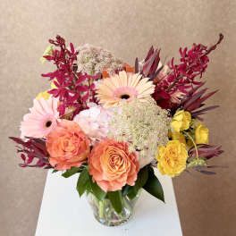 Mixed bouquet of roses and gerbera daisies in a clear glass vase