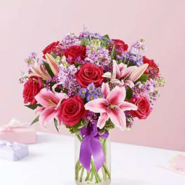 Bouquet of pink lilies and red roses in a glass vase
