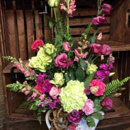 Mixed pink and green floral arrangement in a white ceramic pitcher