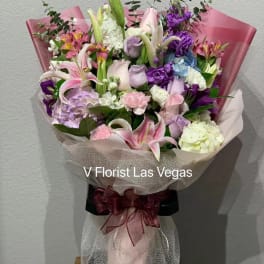 Bouquet of pink, purple, and white flowers wrapped in pink paper