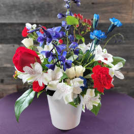 Mixed bouquet of red, white, and blue flowers in a white vase