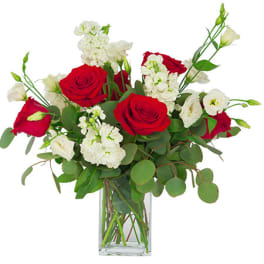 Arrangement of red roses and white flowers in a tall clear glass vase