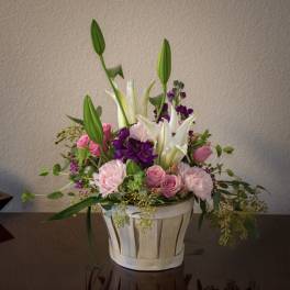 Pink and white floral arrangement in a basket with tall lily buds