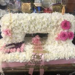 White floral arrangement with pink roses and a pink ribbon on a pink base