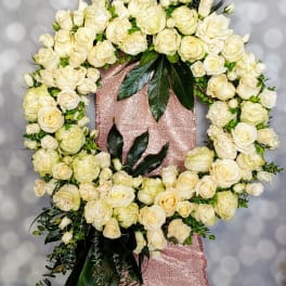 Large white rose wreath on a pink sequined stand