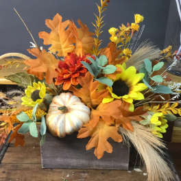 Autumn floral arrangement with sunflowers, orange blooms, and a decorative pumpkin