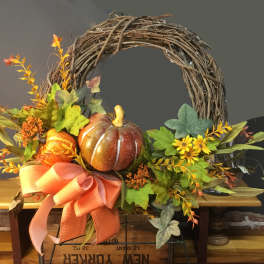 Fall wreath with pumpkins, yellow flowers, and a large orange ribbon