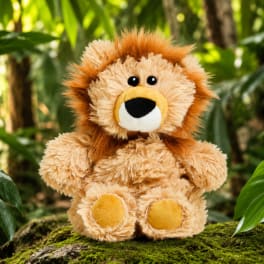 Plush lion sitting on moss with tropical plants in the background