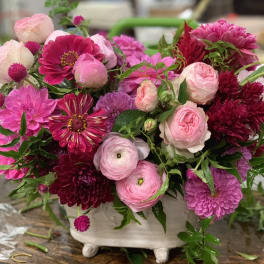 Pink and magenta mixed flowers arranged in a white footed vase
