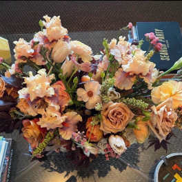 Peach and cream floral arrangement with roses and iris on a table
