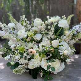 Large white floral arrangement with mixed blooms and berries