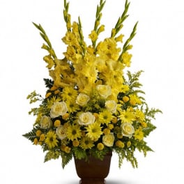 Tall yellow floral arrangement in a brown urn vase