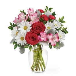 Bouquet of red roses, pink alstroemeria, and white daisies in a clear glass vase