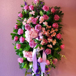 Pink rose funeral spray with ribbons on an easel