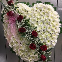 Heart-shaped white chrysanthemum arrangement with red roses and pink ribbon