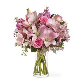 Pink lilies and roses arranged in a clear glass vase