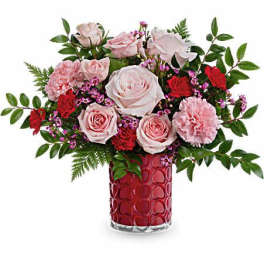 Pink and red flower arrangement in a red glass vase
