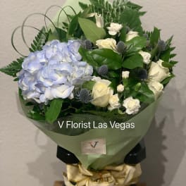 Bouquet of blue hydrangea and white roses wrapped in green paper