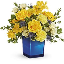 Yellow and white flower arrangement in a blue glass vase