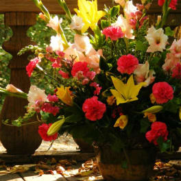 Large mixed flower arrangement in a dark pot with pink, yellow, and white blooms