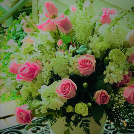 Pink roses and white flowers arranged in a white vase