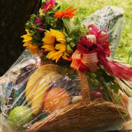 Basket gift with sunflowers and fruit wrapped in clear cellophane