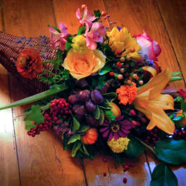 Cone-shaped floral arrangement with roses, lilies, and berries on a wooden floor