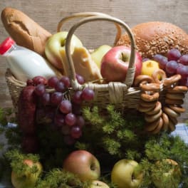 Basket of bread, apples, grapes, cheese, and a milk bottle