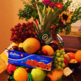 Fruit basket with a floral arrangement and a box of chocolates