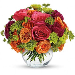Bouquet of pink, orange, and burgundy flowers in a clear glass vase