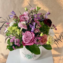 Pink and purple mixed flower arrangement in a white vase