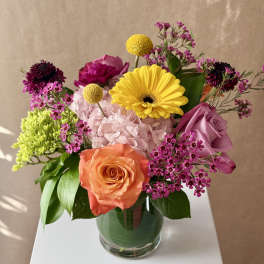 Mixed bouquet in a glass vase with roses, hydrangea, and bright yellow blooms