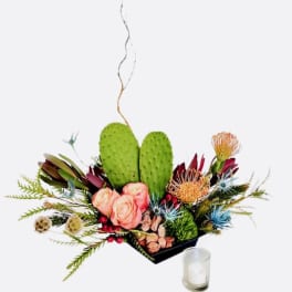 Floral arrangement with pink roses, protea, and cactus pads in a black container