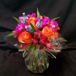 Bouquet of orange roses and magenta flowers wrapped in clear plastic