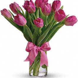 Pink tulip bouquet in a clear glass vase with a pink ribbon