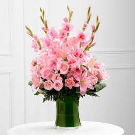 Pink lilies, roses, and carnations in a green glass vase