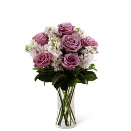 Pink roses and white filler flowers in a clear glass vase