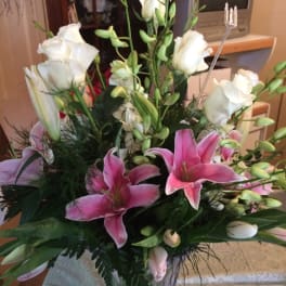 Pink and white lilies arranged in a clear glass vase